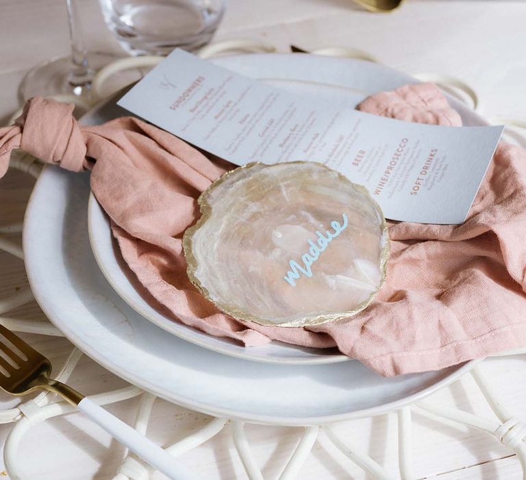 White plates with white and pink wedding stationery menu and name tags on crystal slices