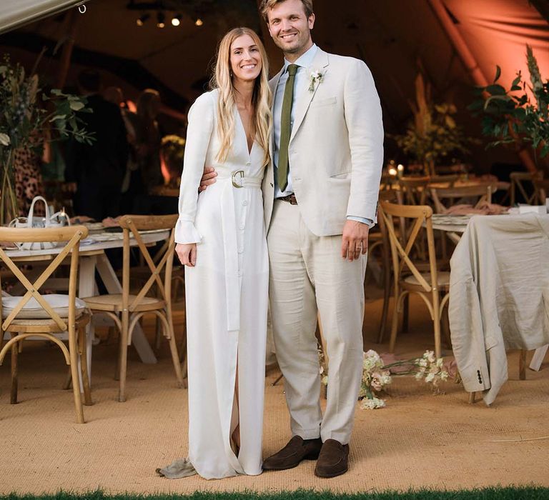 Bride in relaxed Bon Bride wedding dress with buttons and front slit with groom in front of the Buffalo Tipi