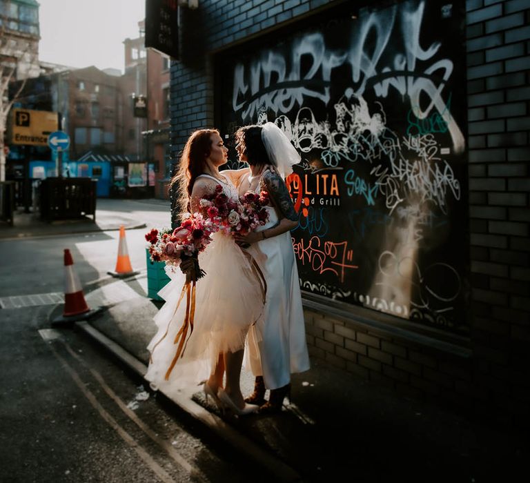 LGBTQI urban wedding photograph with two brides in a layered tulle weddng dress and satin slip 