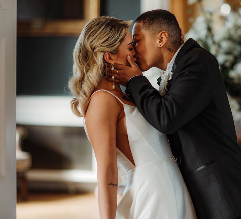 LGBTQI+ couple kissing at luxe Hodsock Priory wedding with the bride wearing a princess wedding dress with sheer side panel 