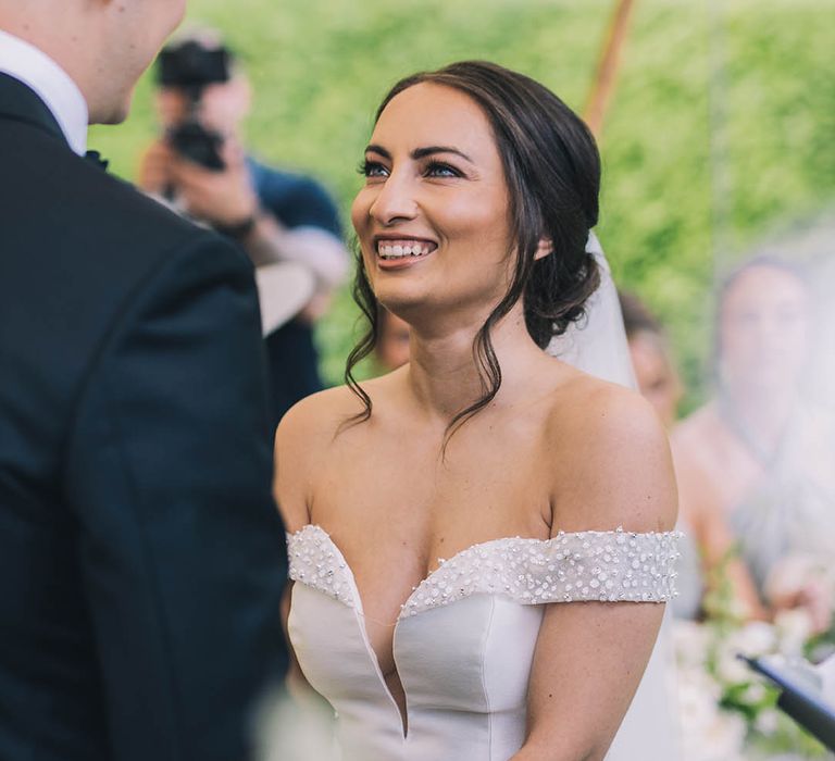 Bride in sparkly off the shoulder v-neck Pronovias wedding gown smiles at her groom