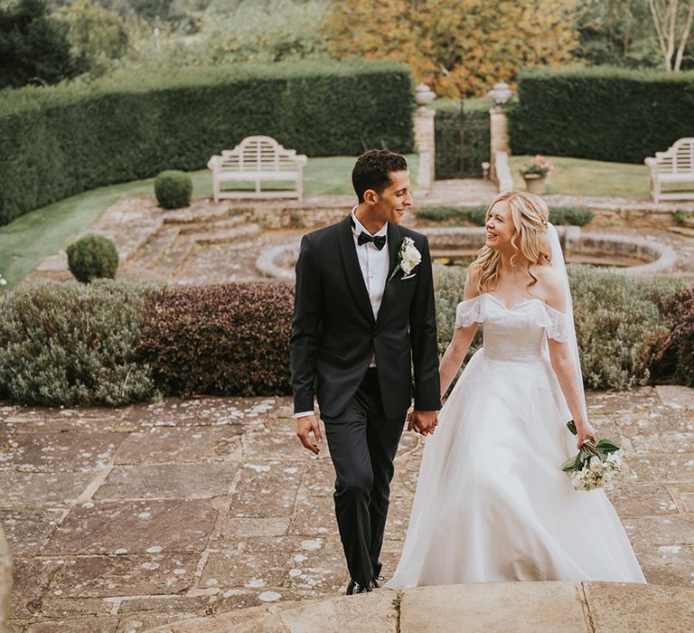 Bride and groom walk up stairs holding hands for their traditional wedding 