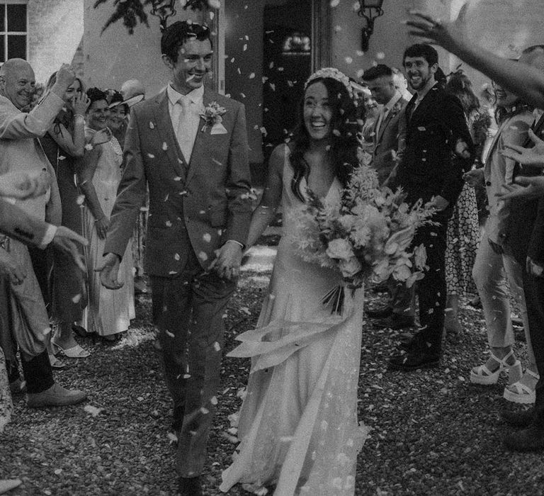 Bride and groom smile happily as they exit their wedding ceremony to confetti 