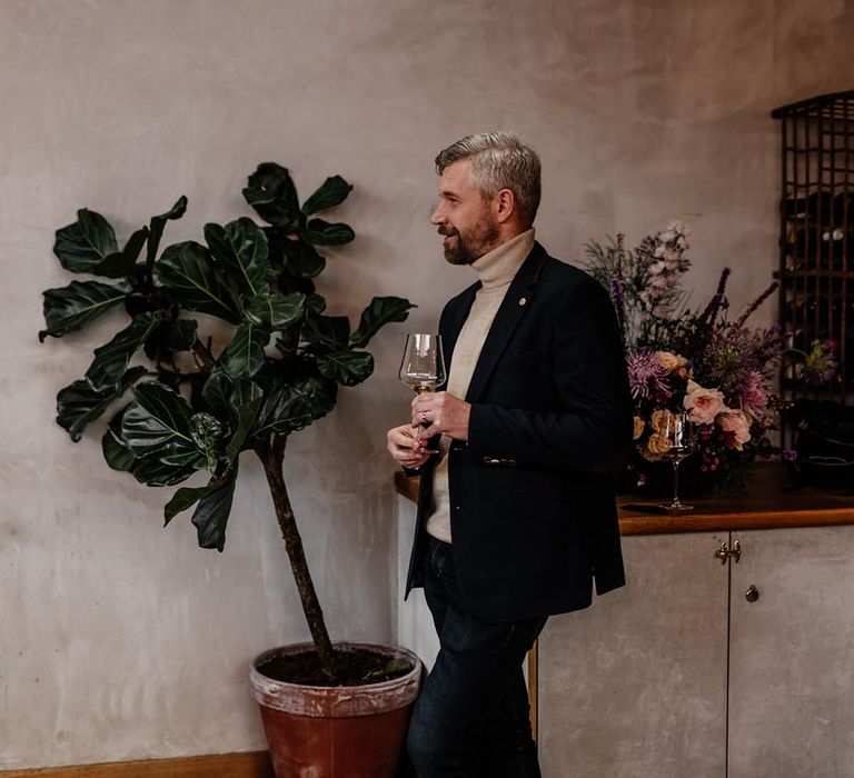 Wedding guest in a beige turtle neck and suit jacket giving a speech 