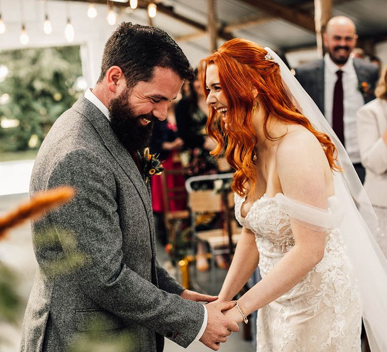 Bride and groom laugh together as they stand at the altar 