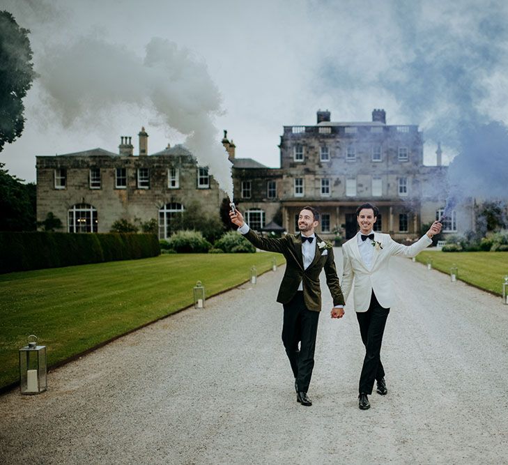 Grooms carry grey & blue smoke bombs outside Birdsall House on their wedding day