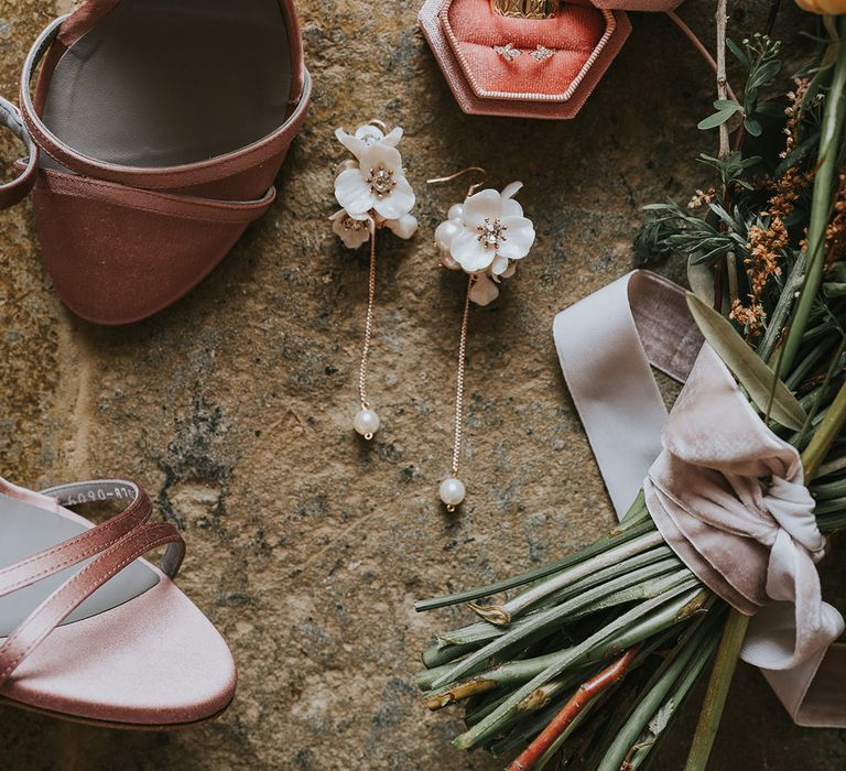 Pink wedding shoes with a pink velvet ring box with unique gold wedding bands with white flower earrings with pearls 