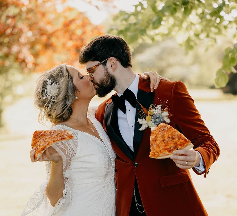 Bride and groom kiss as they eat slices of pizza for their fun wedding at Gracehall 