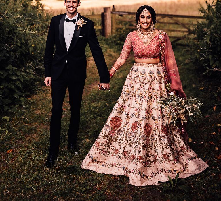 Bride & groom walk outdoors in the countryside at Bredenbury Court Barns