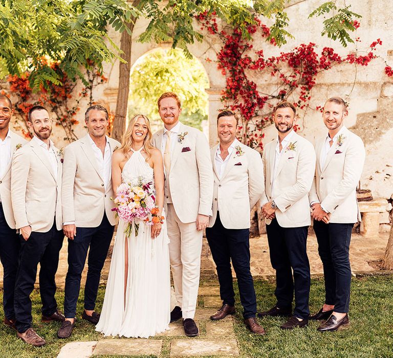 Bride and groom with the groomsmen in matching cream suits for the rustic destination wedding 