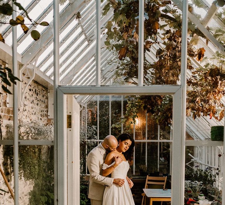 Bride and groom share an intimate moment in the glasshouse at the Chapel House Estate 