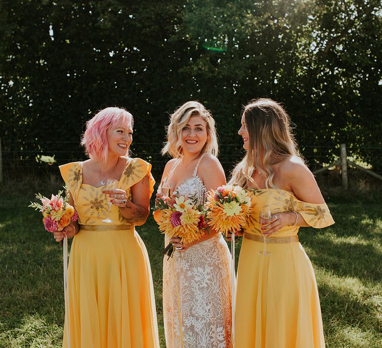 Bridesmaids wearing bright canary yellow dresses with gold embroidery