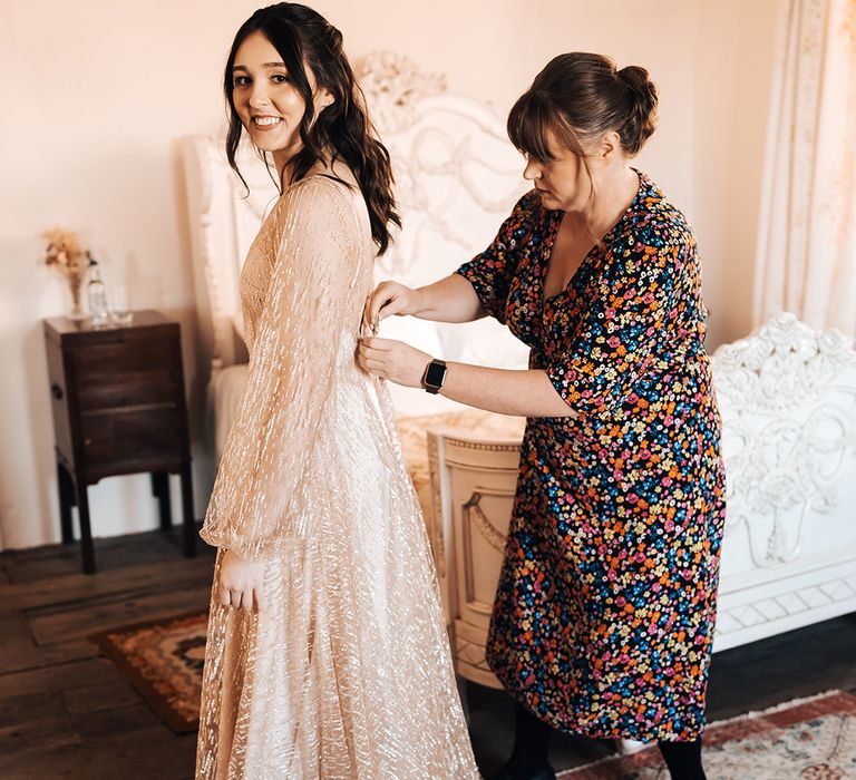 Bride wears sheer gold long sleeve wedding dress with buttoned back 