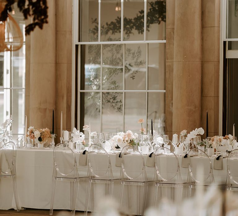 Neutral and black taper candles decorate the tablescape with pale pink and white wedding flowers 