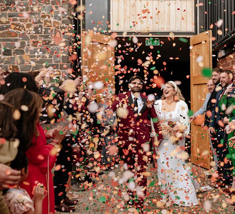 The wedding guests throw confetti from Flutter, Darlings! over the bride and groom 