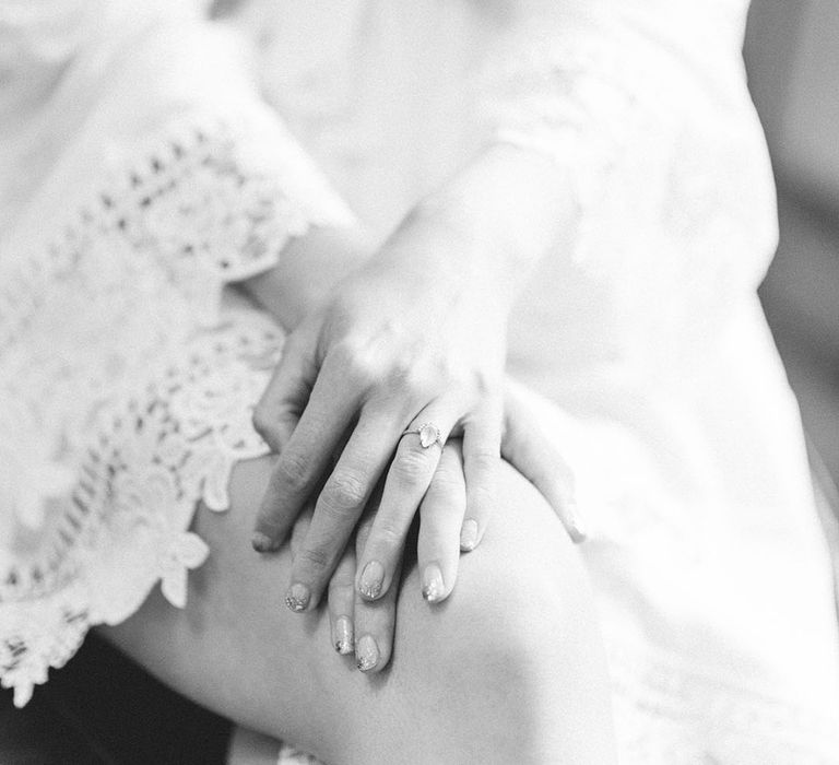 Bride wears sparkling nail polish and oval shaped diamond engagement ring in black & white photo