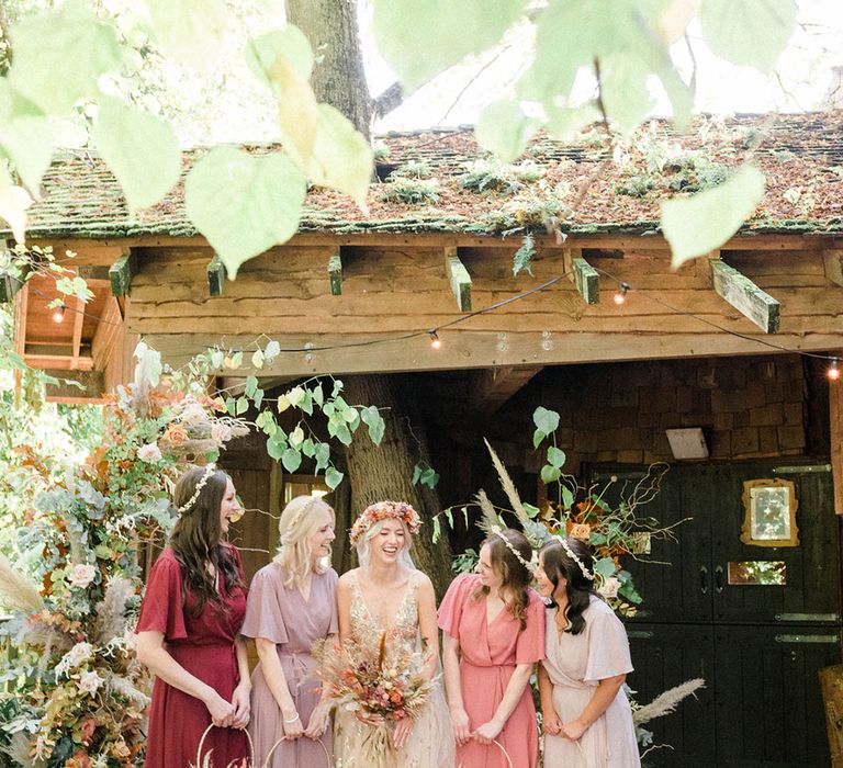 Bride stands with her bridesmaids in Rewritten Bridesmaid dresses in mismatched colours 