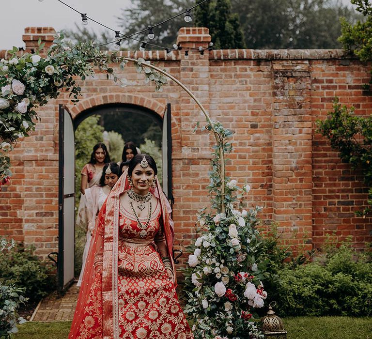 Bride walks through beautiful gardens at Braxted Park Estate for Hindu wedding ceremony 