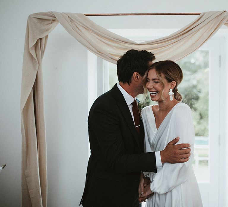 Bride wears silk wrap wedding dress complete with bell sleeves and timeless style 