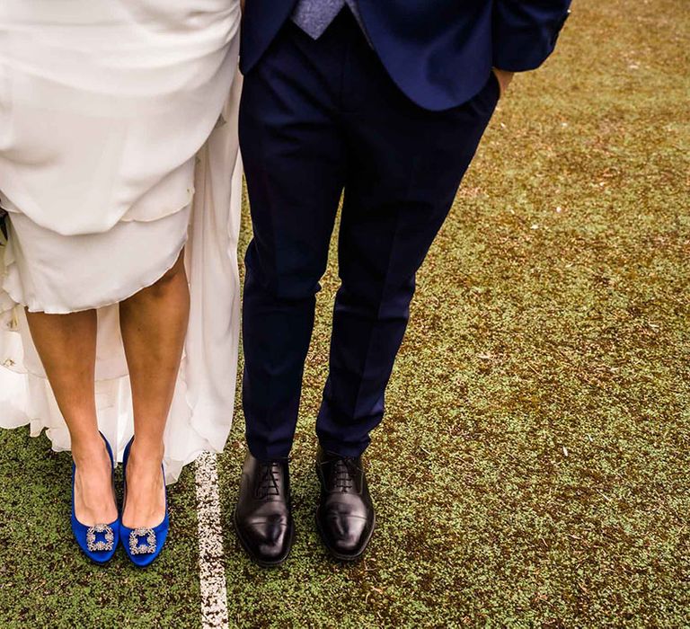 Bride wears blue Manolo Blahnik heels beside groom in Loake wedding shoes