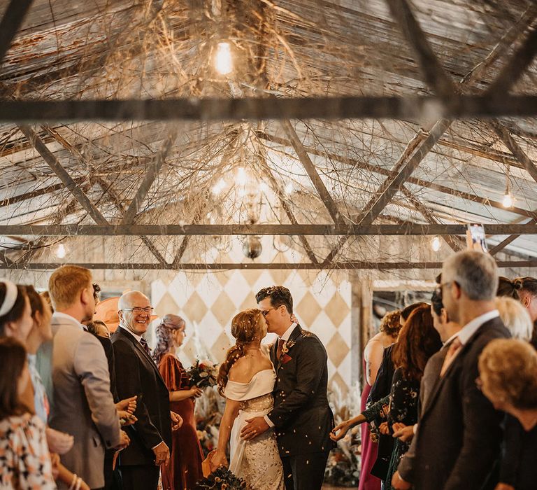 Bride & groom walk through colourful confetti exit at The Dreys after bespoke wedding ceremony 