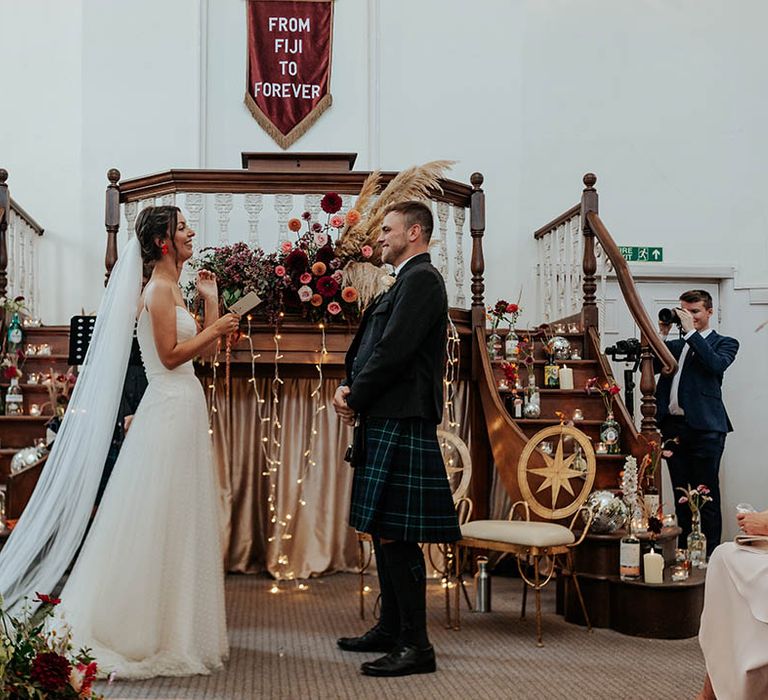 Bride in a Stephanie Allin wedding dress and groom in a kilt exchange personalised wedding vows at bespoke wedding ceremony 