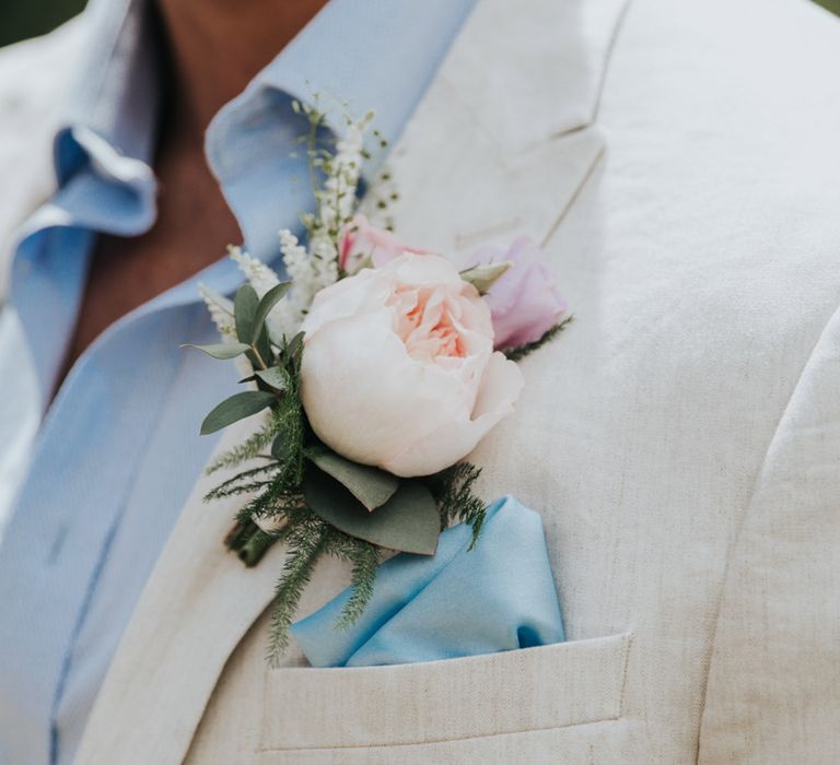 Groom in summer white suit with baby blue shirt and pocket square with pink peony buttonhole 