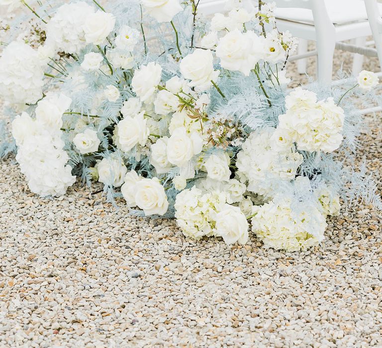 White rose and hydrangea wedding flowers with baby blue dyed grass for outdoor wedding ceremony 