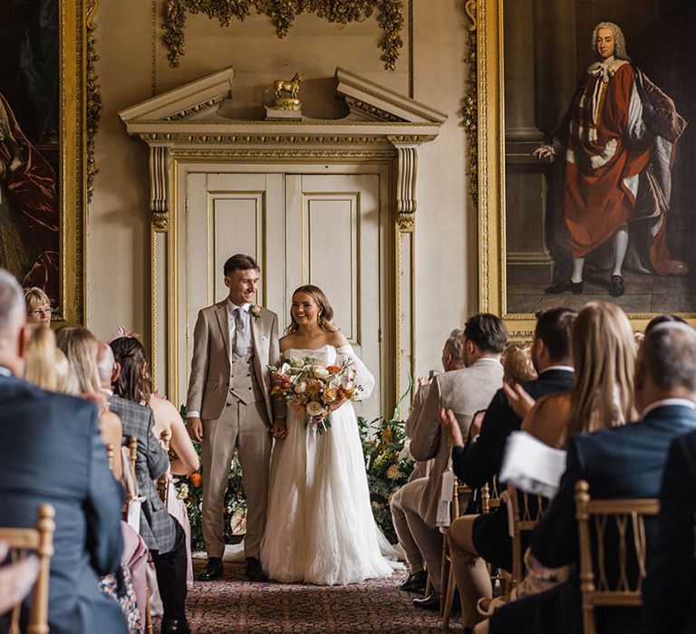 The bride and groom walk back down the aisle as a married couple for their country house wedding in Dorset 