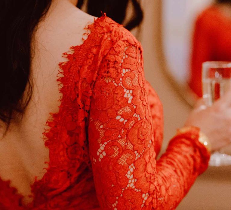 Close up of delicate bow and v-back details of red lace wedding dress with long sleeves 