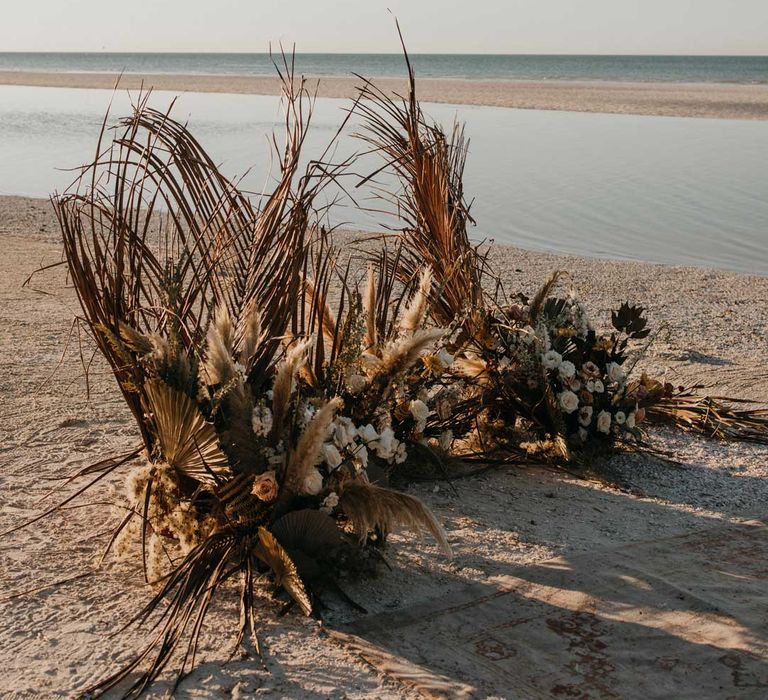 Large pampas grass and dried flower wedding flower arrangement on beach at destination wedding in Mexico 