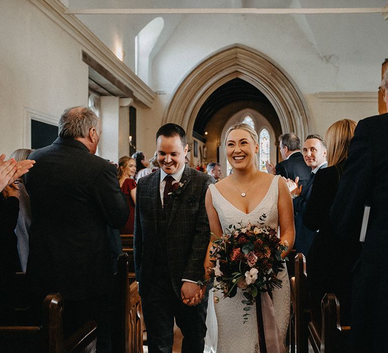 Bride and groom walk back down the aisle as a married couple 