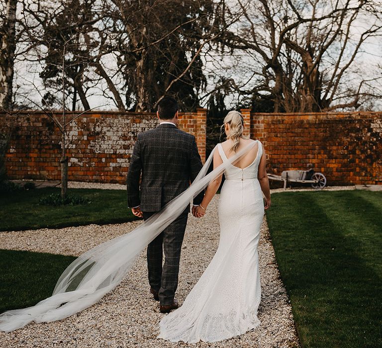 Bride in Karen Willis Holmes wedding dress walking with the groom around the wedding venue 