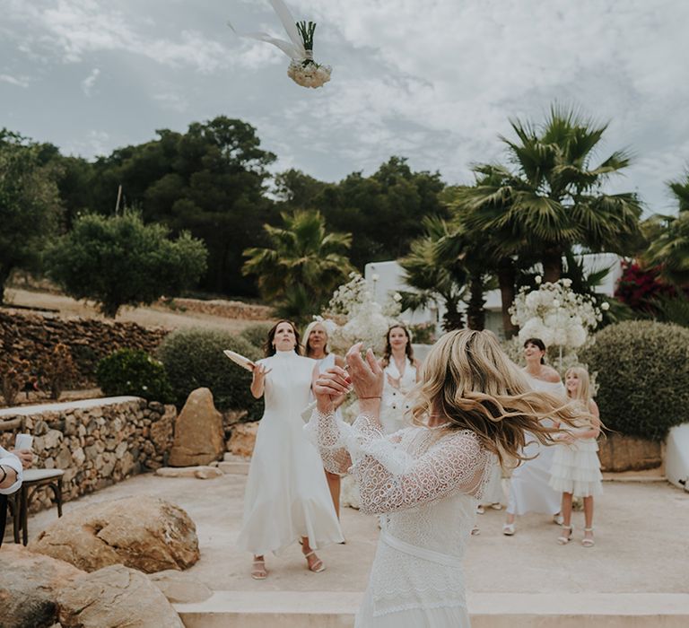 bride with bell sleeves tossing her bouquet at pure house ibiza wedding