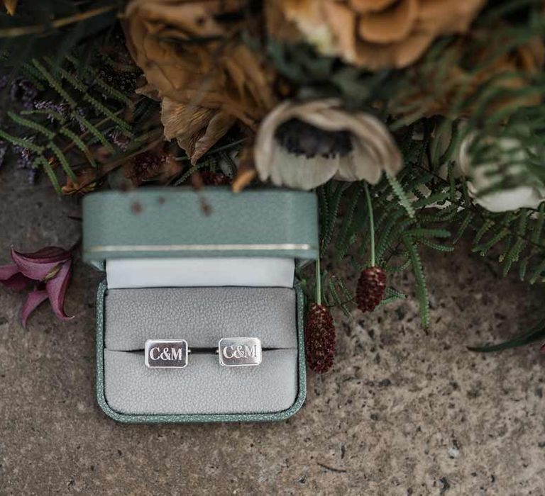 Personalised silver wedding cufflinks in sage green cufflinks box next to dried wildflower wedding bouquet at Buxted Park