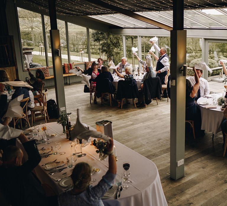 Wedding guests wave their wedding napkins as the bride and groom enter the Stone Barn wedding reception 