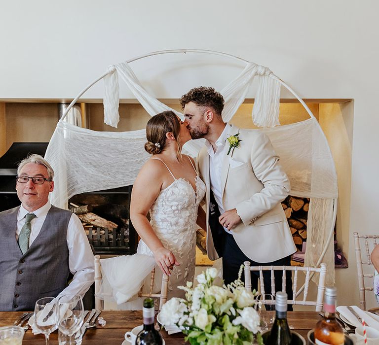 The bride and groom share a kiss at their wedding breakfast 