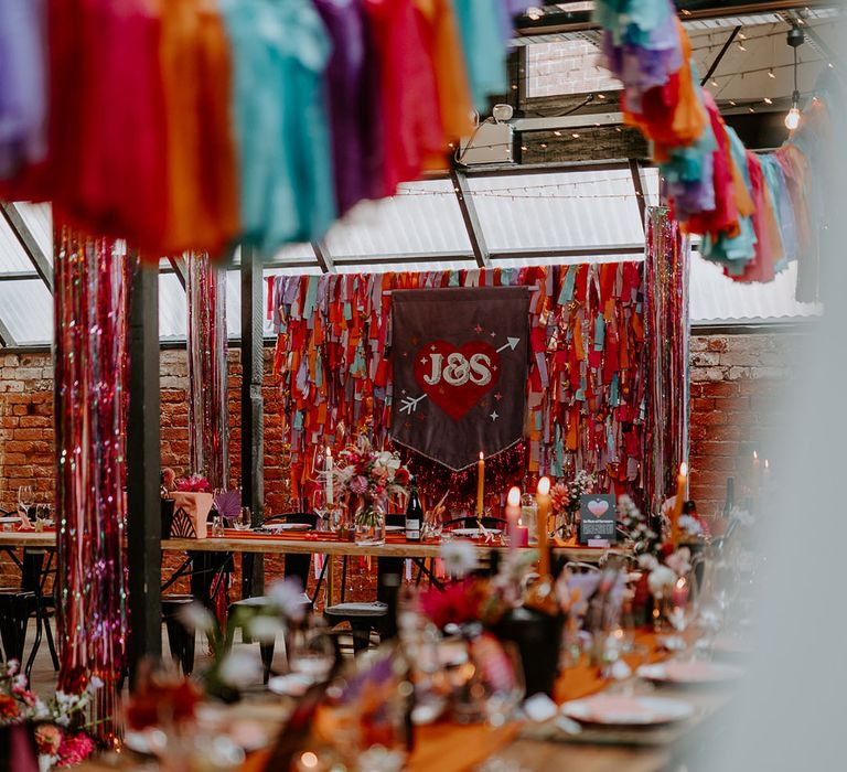 Industrial wedding venue decorated in colourful rainbow streamers with a banner sign 