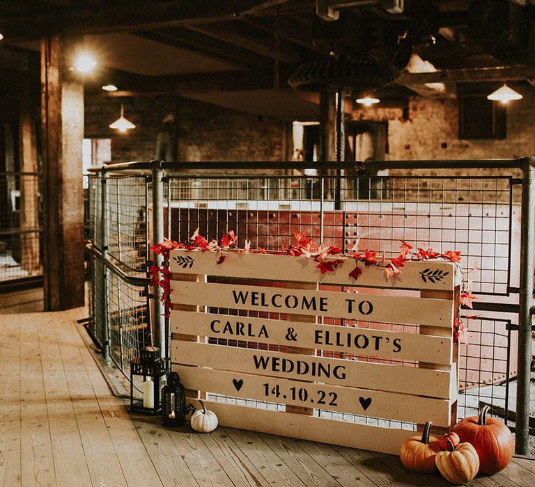 Wedding welcome sign DIY'd out of a wooden pallet with autumn leaves, pumpkins and gourds for October wedding 