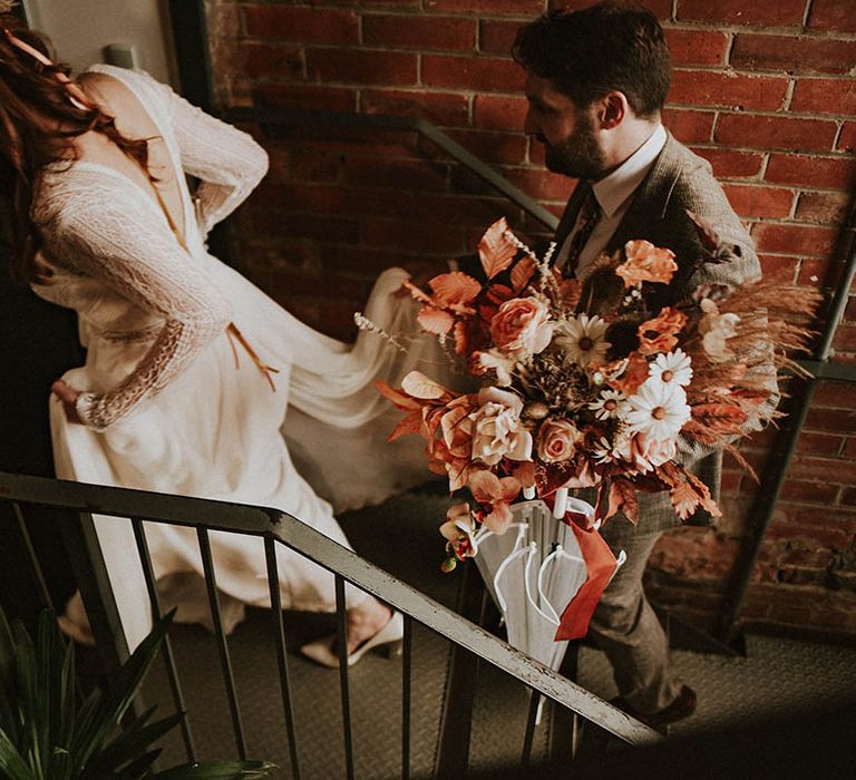 Bride and groom walking upstairs to their wedding reception at Northern Monk Brewery 