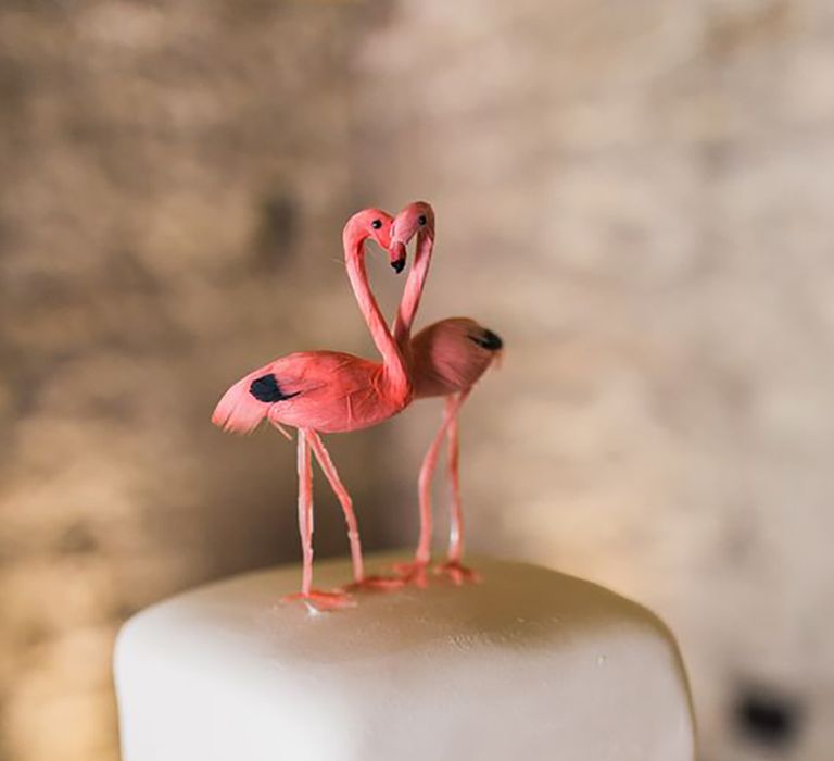 Flamingo cake topper sitting on top of white wedding cake