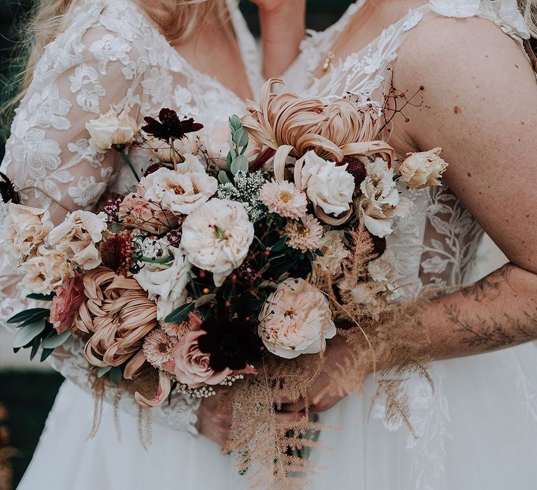 Two brides carry autumnal bouquets with peonies and anemones 