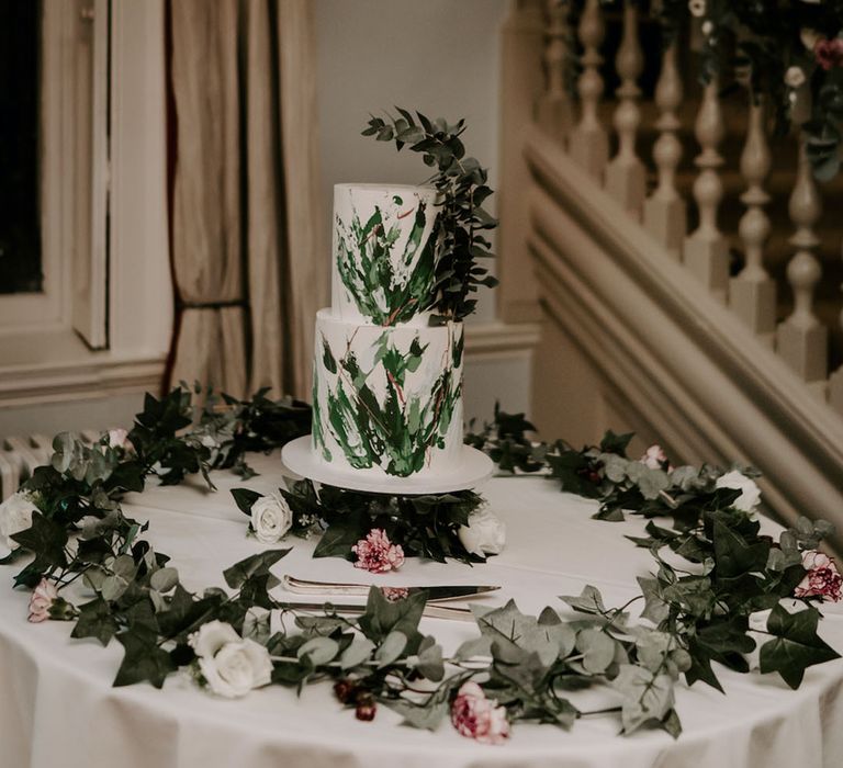 Two tier white iced wedding cake with green frosting designed to look like leaves and foliage for botanical wedding cake 