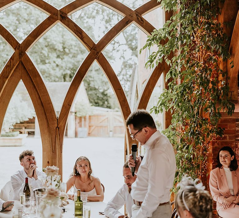 Wedding speeches at Shustoke Barns wedding with stunning arched windows 