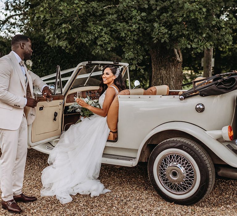 Bride sits in classic vintage wedding car at traditional wedding 