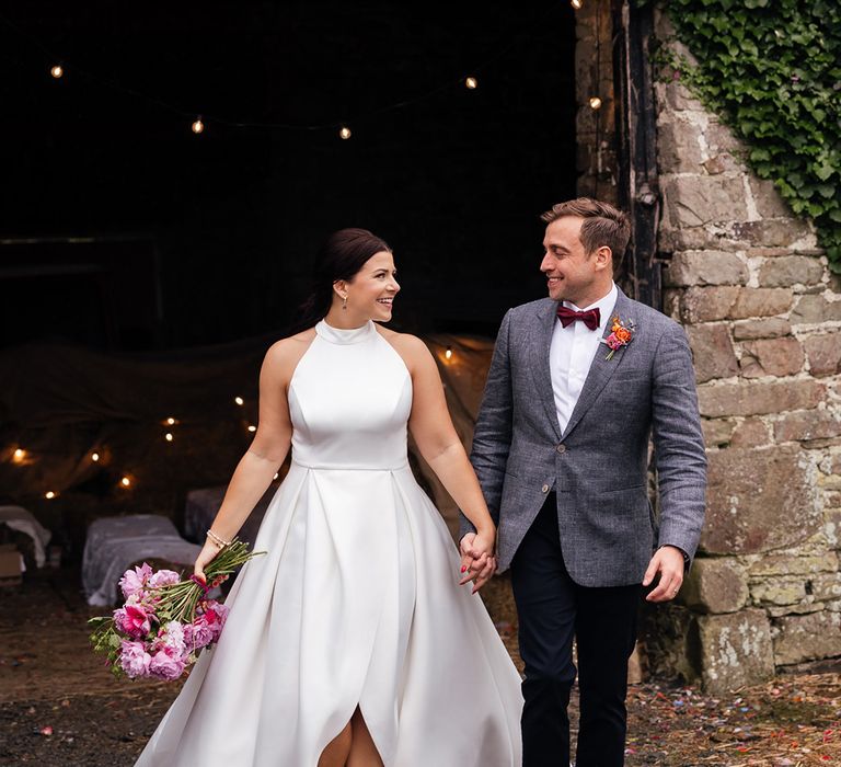 Bride wears halter neck wedding dress with the groom in a dark grey wedding suit 