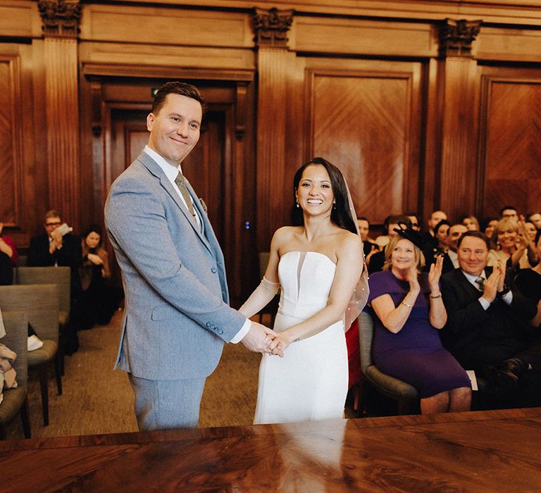 The bride and groom hold hands for their wedding ceremony at Old Marylebone Town Hall