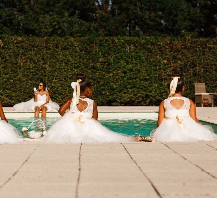 Cute flower girls with yellow ribbons sit by the pool