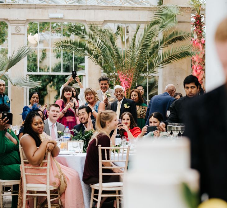 Wedding guests watching the bride and groom cutting the wedding cake