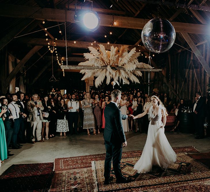 Bride and groom first dance in a barn with pampas grass floral installation